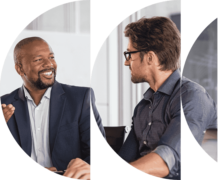 Two men in a professional setting engaging in a conversation, one smiling and the other listening attentively.